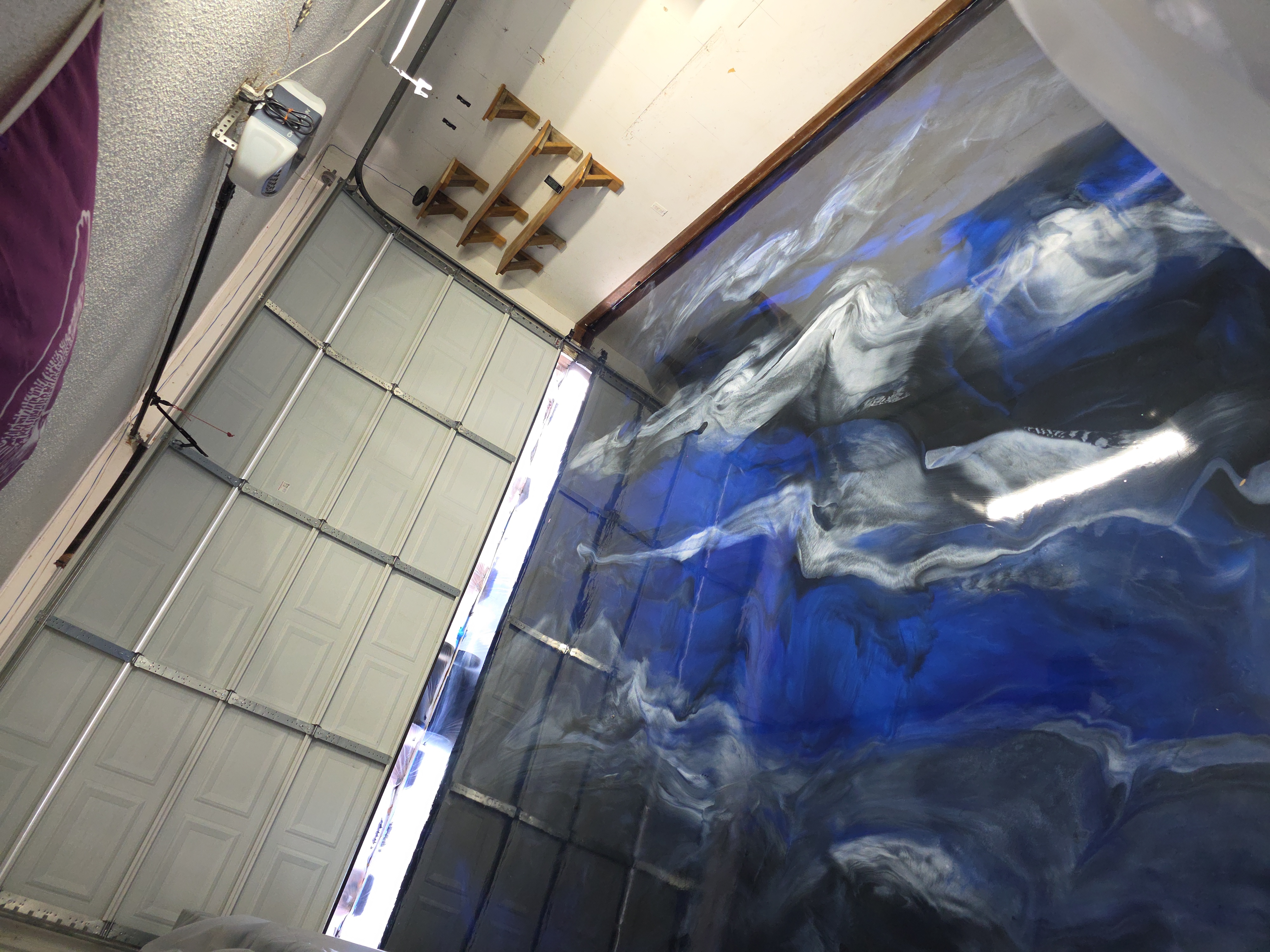 Blue and silver metallic epoxy garage floor with flowing wave patterns