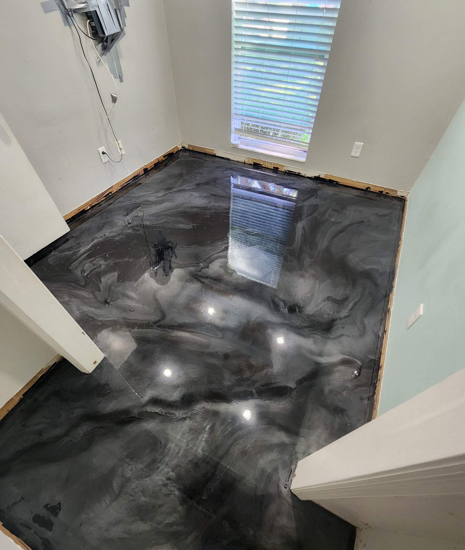Dark charcoal metallic epoxy floor with silver marble swirls in a residential space